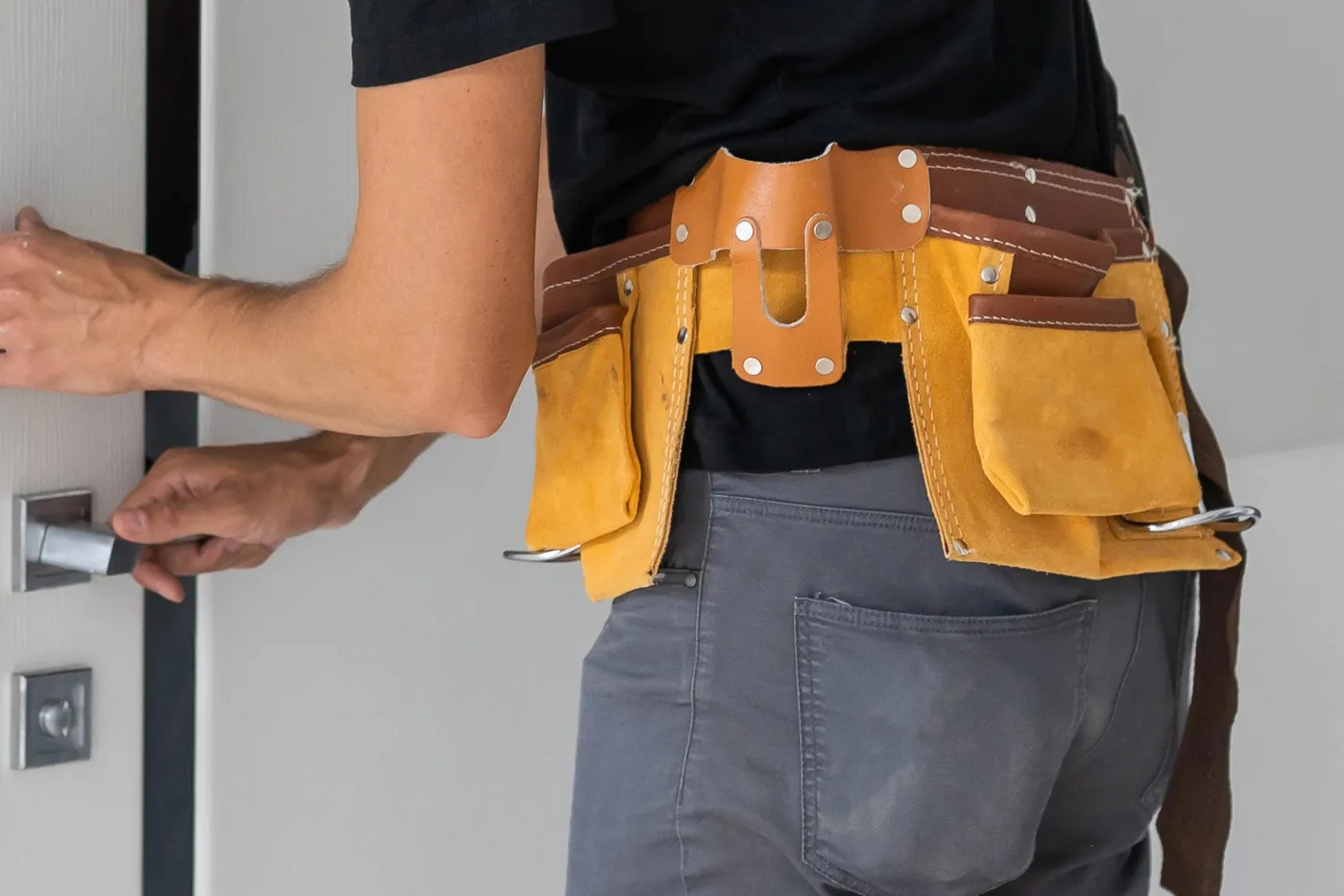Artisan serrurier en ceinture à outils intervenant sur la serrure d'une maison à Noisy-le-Roi